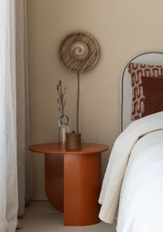 Runde Wandleuchte It's about RoMi Tivoli aus Travertin in Sand an beige Wand, daneben oranger Beistelltisch und Bett.