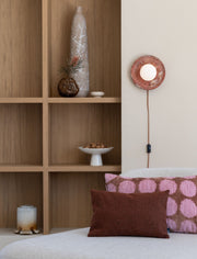 It's about RoMi Wandleuchte Tivoli in Terrakotta: runde Wandleuchte mit Glaskugel, an Holzregal und Sofakissen montiert.