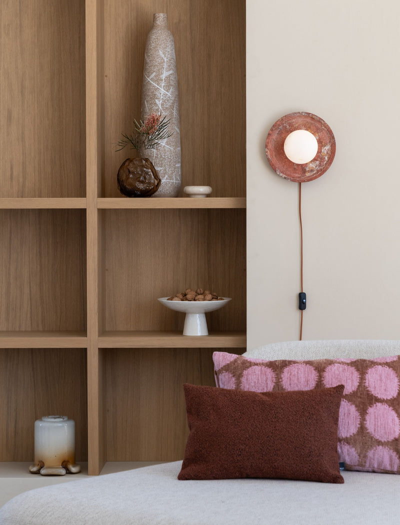 It's about RoMi Wandleuchte Tivoli in Terrakotta: runde Wandleuchte mit Glaskugel, an Holzregal und Sofakissen montiert.