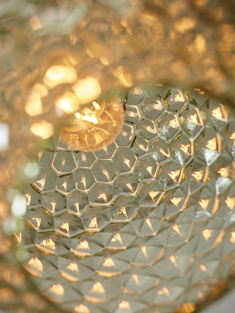 Detailansicht der Hängeleuchte It's about RoMi Venice aus grünlichem Glas mit wabenförmiger Facettenstruktur, durch die warmes Licht schimmert.