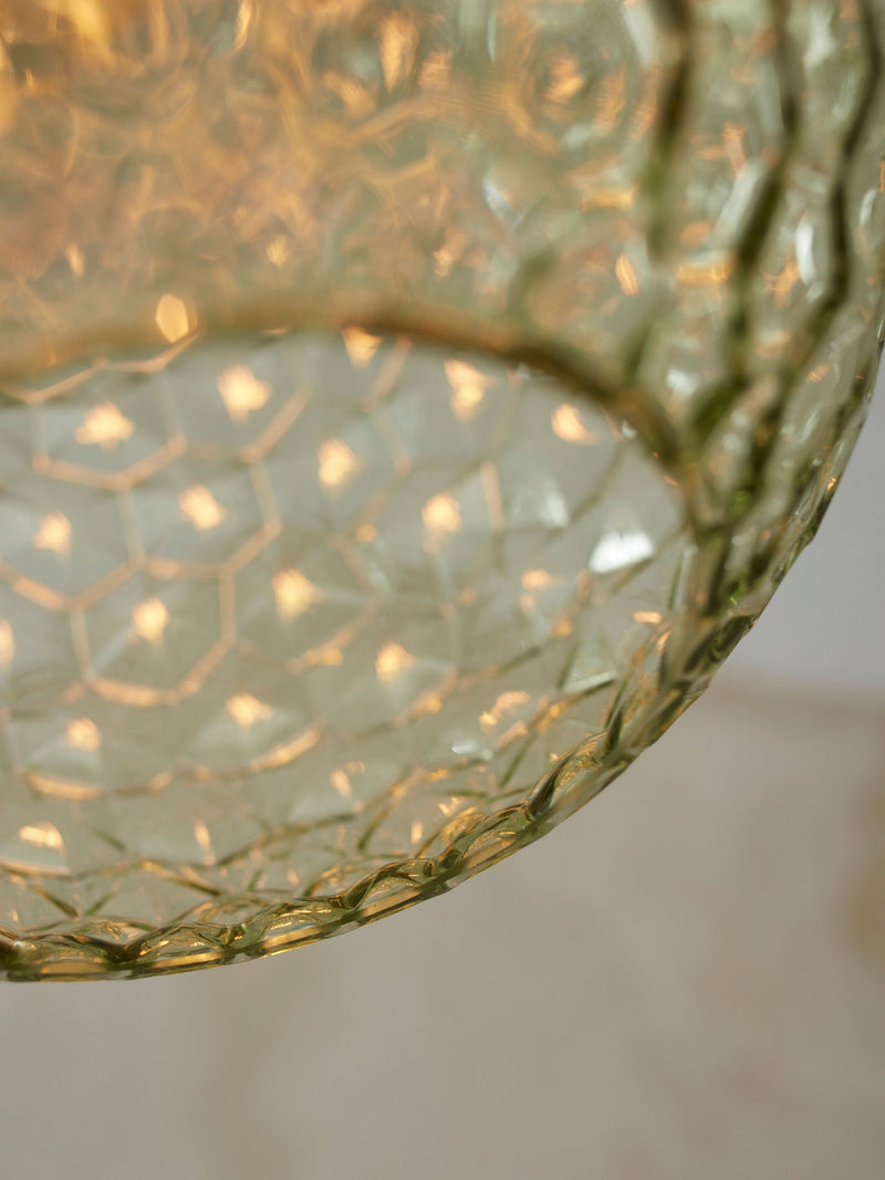 Detailaufnahme des grünlich-goldenen Glasschirms der Hängeleuchte It's about RoMi Venice mit warmem Lichtschimmer