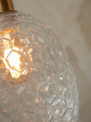 Detailansicht der Hängeleuchte „It's about RoMi Hängeleuchte Venice“ mit wabenförmigem Glasschirm und warm leuchtender Glühbirne.