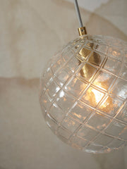 Detailansicht der Hängeleuchte It's about RoMi Venice mit klarem, facettiertem Glasschirm im Gittermuster und goldfarbenem Aufhängungsring.