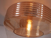 Deckenleuchte Verona aus bernsteinfarbenem Glas: Detailansicht des gerillten Glasschirms mit Leuchtmittel.