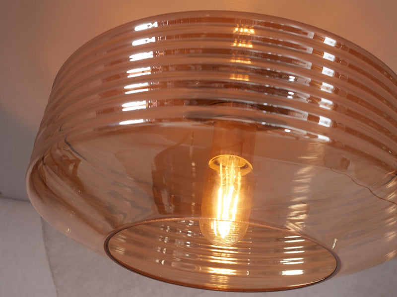 Deckenleuchte Verona aus bernsteinfarbenem Glas: Detailansicht des gerillten Glasschirms mit Leuchtmittel.