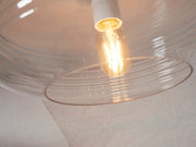 Detailansicht der klaren Glas-Deckenleuchte It's about RoMi Verona mit sichtbar leuchtender Filament-Glühbirne im Schirm.