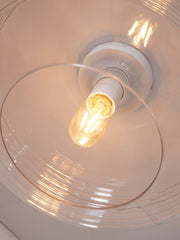 Detailansicht der RoMi Deckenleuchte Verona aus Glas mit klarem Glasschirm und brennender Glühlampe.