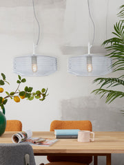 Zwei Hängeleuchten „It's about RoMi Verona“ aus klarem, geripptem Glas über einem Holztisch mit Zeitschriften und Tasse.