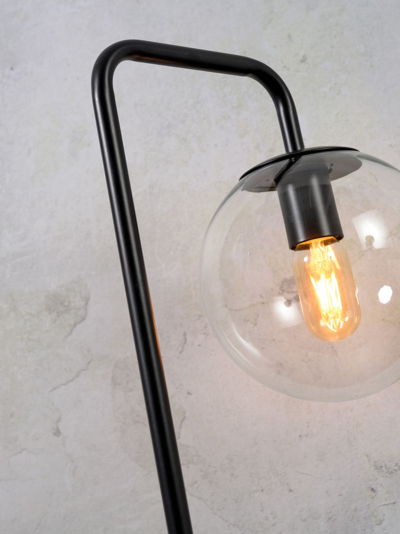 Detailansicht der schwarzen Tischleuchte It's about RoMi Warsaw mit gebogenem Eisenarm und Glaskugel mit Glühlampe.