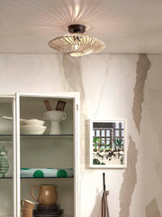 Flache Deckenleuchte Zanzibar aus weißem Rattan mit dunklem Eisengestell, die ein sternförmiges Lichtmuster an die Decke wirft.