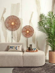 Zwei runde Rattan-Wandleuchten in Naturtönen hängen über einem beigen Sofa in einem hellen Wohnraum.