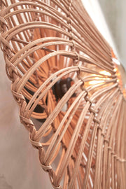 Detailansicht der Good&Mojo Wandleuchte Zanzibar: geflochtene Rattanstreben umrahmen eine warm leuchtende Lichtquelle.