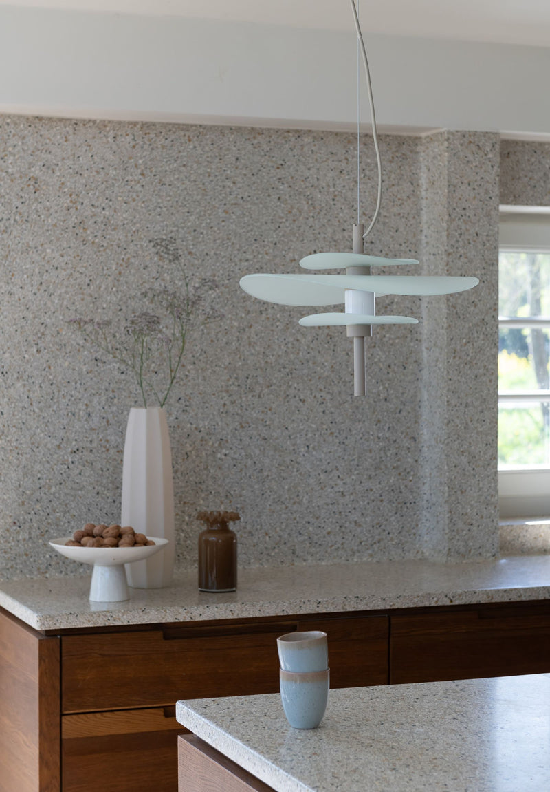 RoMi Hängeleuchte Kyoto in Sand: Mehrere flache, helle Glasschirme hängen über einer Küchenarbeitsplatte mit Terrazzo-Optik.