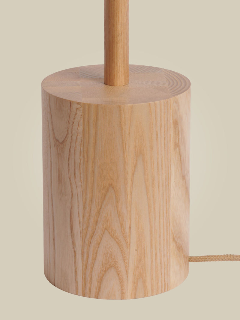 Detailansicht des zylindrischen Lampenfußes der Good&Mojo Stehleuchte Okinawa aus Eschenholz in Natur, mit textilem Kabel.