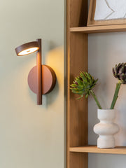 Good&Mojo Wandleuchte Okinawa aus braunem Eschenholz mit leuchtendem Ringschirm an einer hellen Wand.