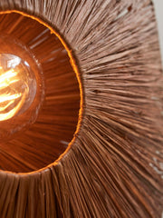 Detailansicht der braunen Deckenleuchte Good&Mojo Panama Raffia Octogon S: Raffiageflecht mit leuchtender Glühbirne im Innern.