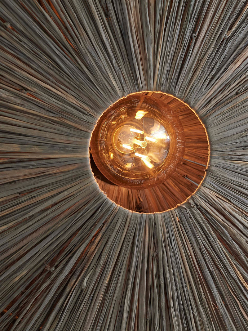 Innenansicht der Deckenleuchte Panama von Good&Mojo: Blick von unten auf den radial geflochtenen Raffia-Schirm mit Glühlampe.
