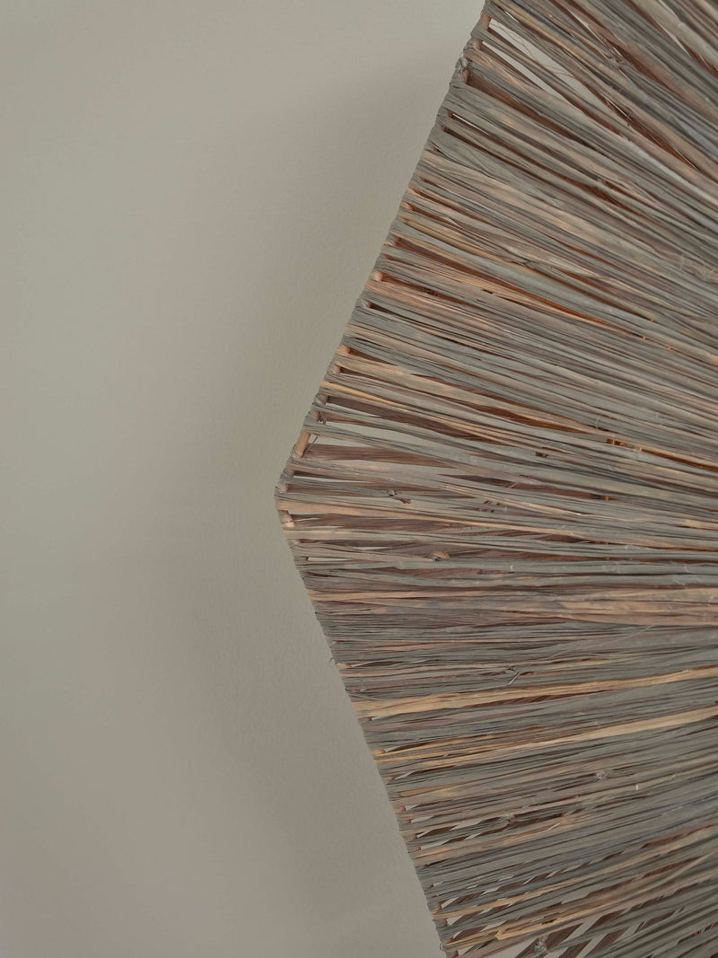 Detailansicht des braunen Raffia-Geflechts der Good&Mojo Deckenleuchte Panama mit ihrer achteckigen Form vor heller Wand.