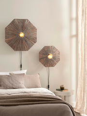 Zwei achteckige Wandleuchten Panama aus braunem Raffia mit Eisenfassung über einem Bett.