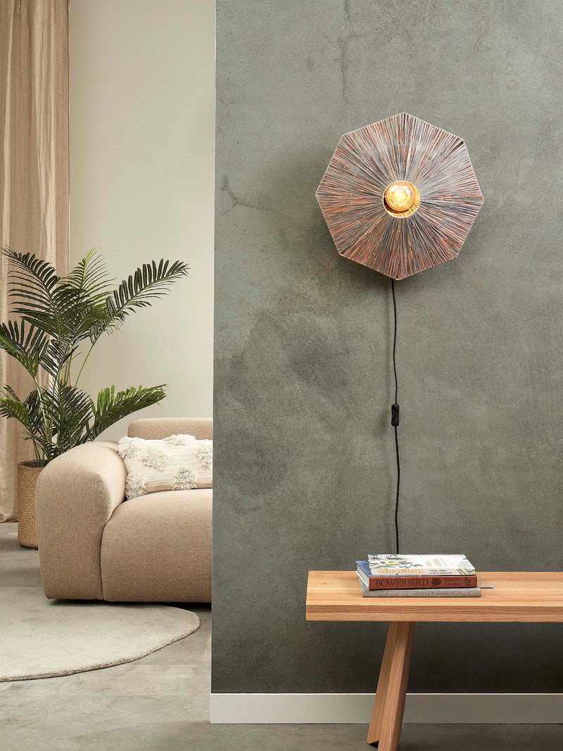 Gesamtansicht der achteckigen Wandleuchte Panama von Good&Mojo aus braunem Raffia an einer grauen Betonwand.