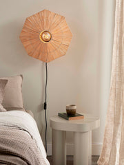 Achteckige Wandleuchte Panama von Good&Mojo aus geflochtenem Raffia, eingeschaltet über einem Nachttisch im Schlafzimmer.