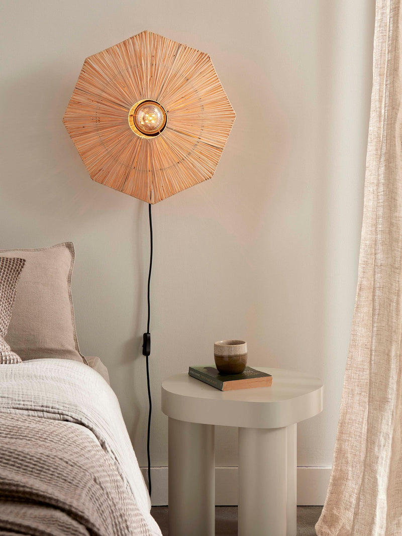 Achteckige Wandleuchte Panama von Good&Mojo aus geflochtenem Raffia, eingeschaltet über einem Nachttisch im Schlafzimmer.