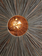 Detailansicht der Good&Mojo Wandleuchte Panama aus Raffia: Blick in den Schirm mit radialen Raffiafasern und Glühbirne.