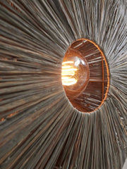 Detailansicht der Good&Mojo Wandleuchte Panama: Blick in den braunen Raffia-Schirm mit brennender Glühlampe.