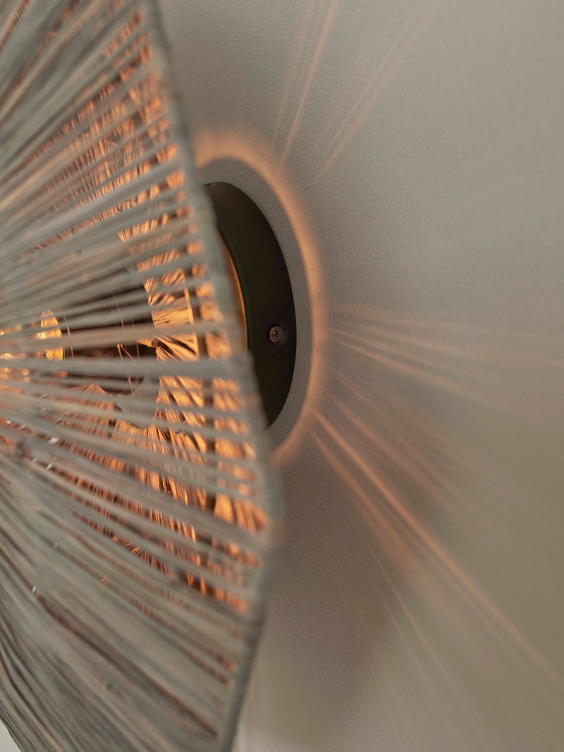 Detailansicht der Good&Mojo Wandleuchte Panama: geflochtener Raffia-Schirm mit warmem Lichtschein, dunkle Wandbefestigung.