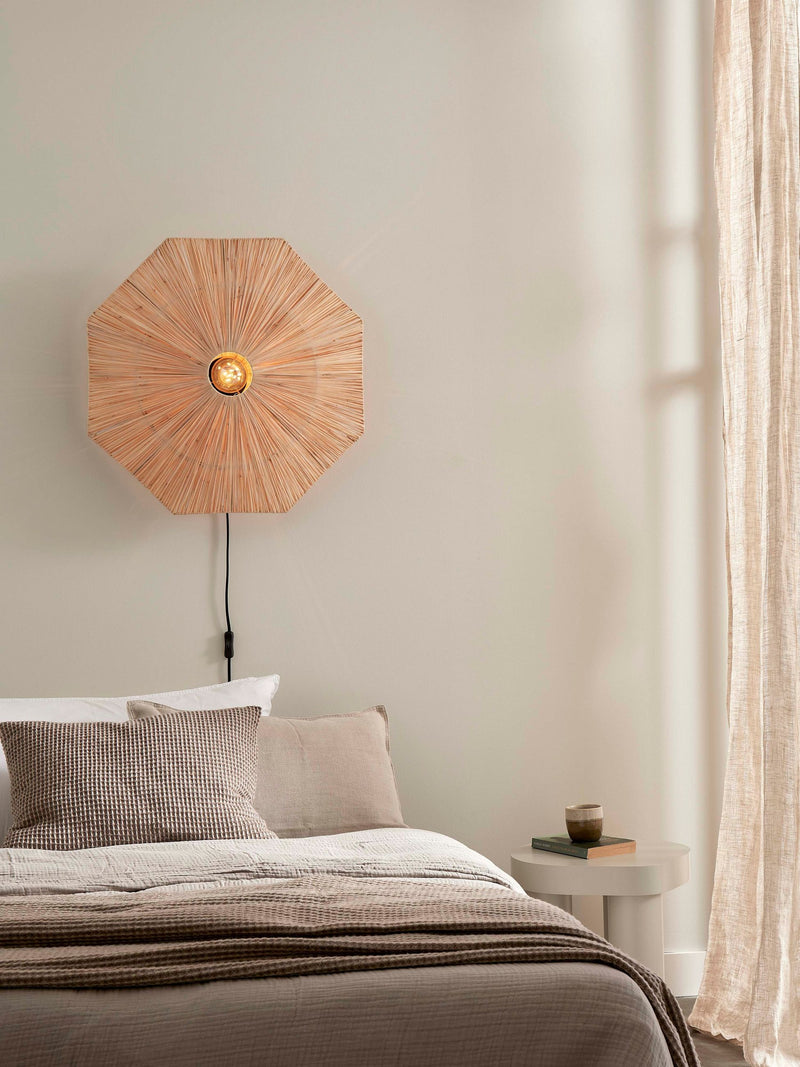 Good&Mojo Wandleuchte Panama aus Raffia: achteckiger, sternförmig geflochtener Schirm über dem Bett, seitlich herabhängendes Kabel.