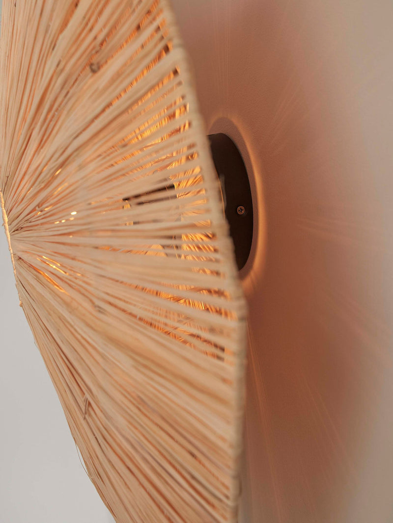 Detailansicht der Wandleuchte Good&Mojo Panama aus Raffia mit strahlenförmig geflochtenem Schirm und dunklem Wandteller.