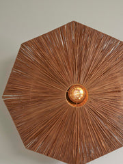 Good&Mojo Wandleuchte Panama aus Raffia: achteckiger Schirm mit radial verlaufenden Raffiafasern, mittig sichtbare Glühlampe.