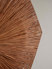 Detailansicht des achteckigen Raffia-Schirms der Good&Mojo Wandleuchte Panama mit radial verlaufenden braunen Fasern vor heller Wand.