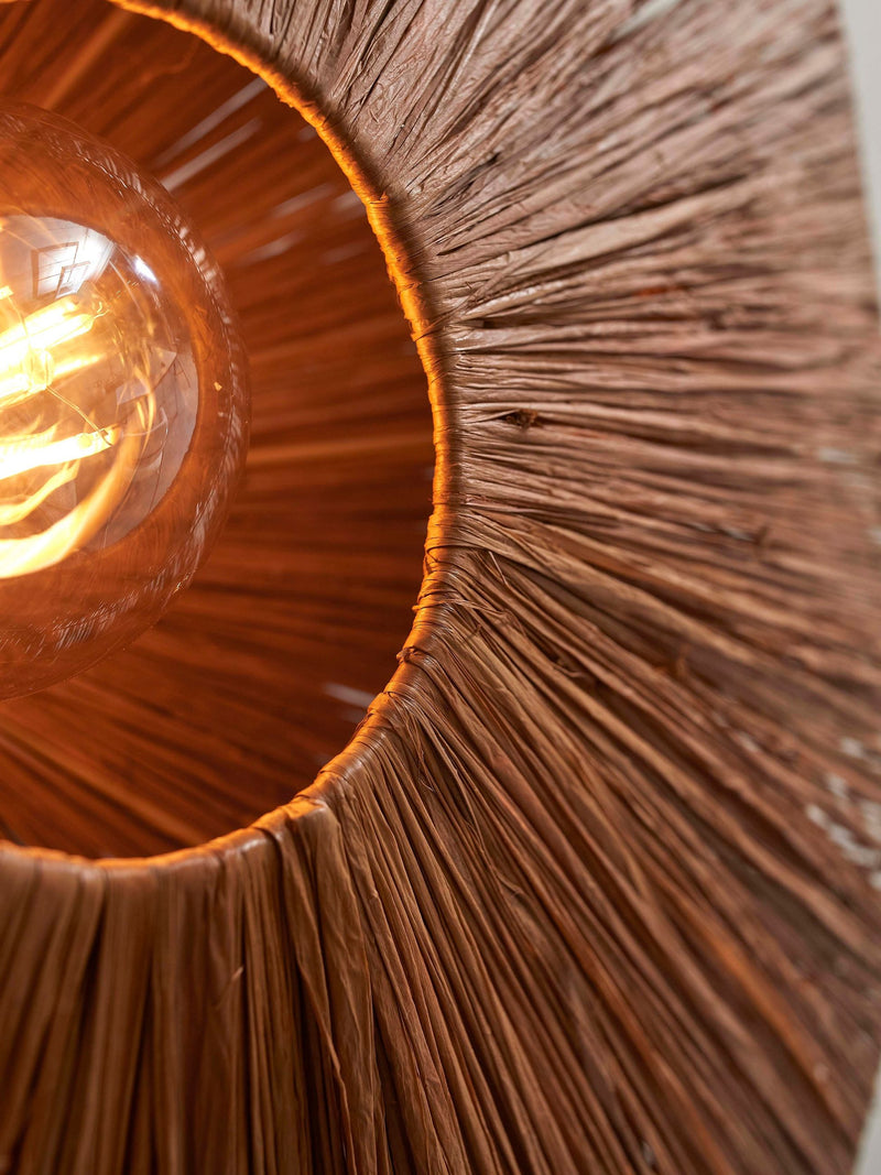 Detailansicht des braunen Raffia-Schirms der Good&Mojo Wandleuchte Panama mit sichtbar leuchtender Glühlampe im Inneren.